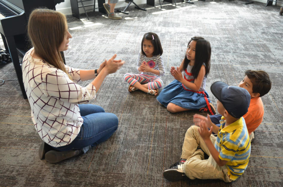 teacher and students sitting on floor