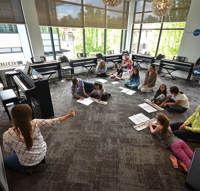 teacher and students on floor practicing piano