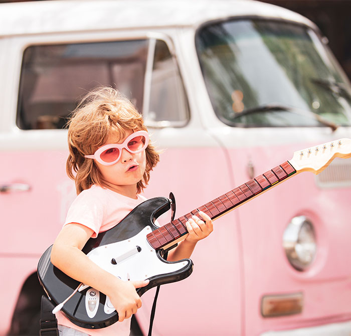 Groovy girl with guitar in front of Pink VW van
