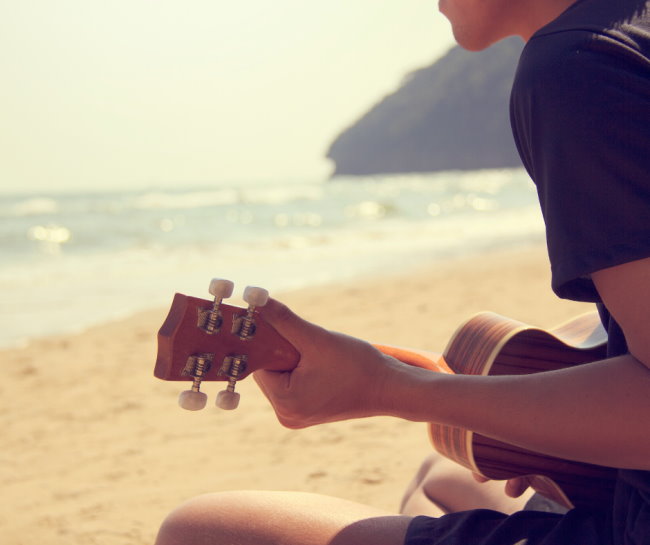 Dude playing a uke on the beach