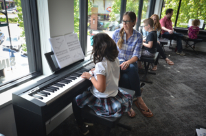 Young lady taking piano lessons in group