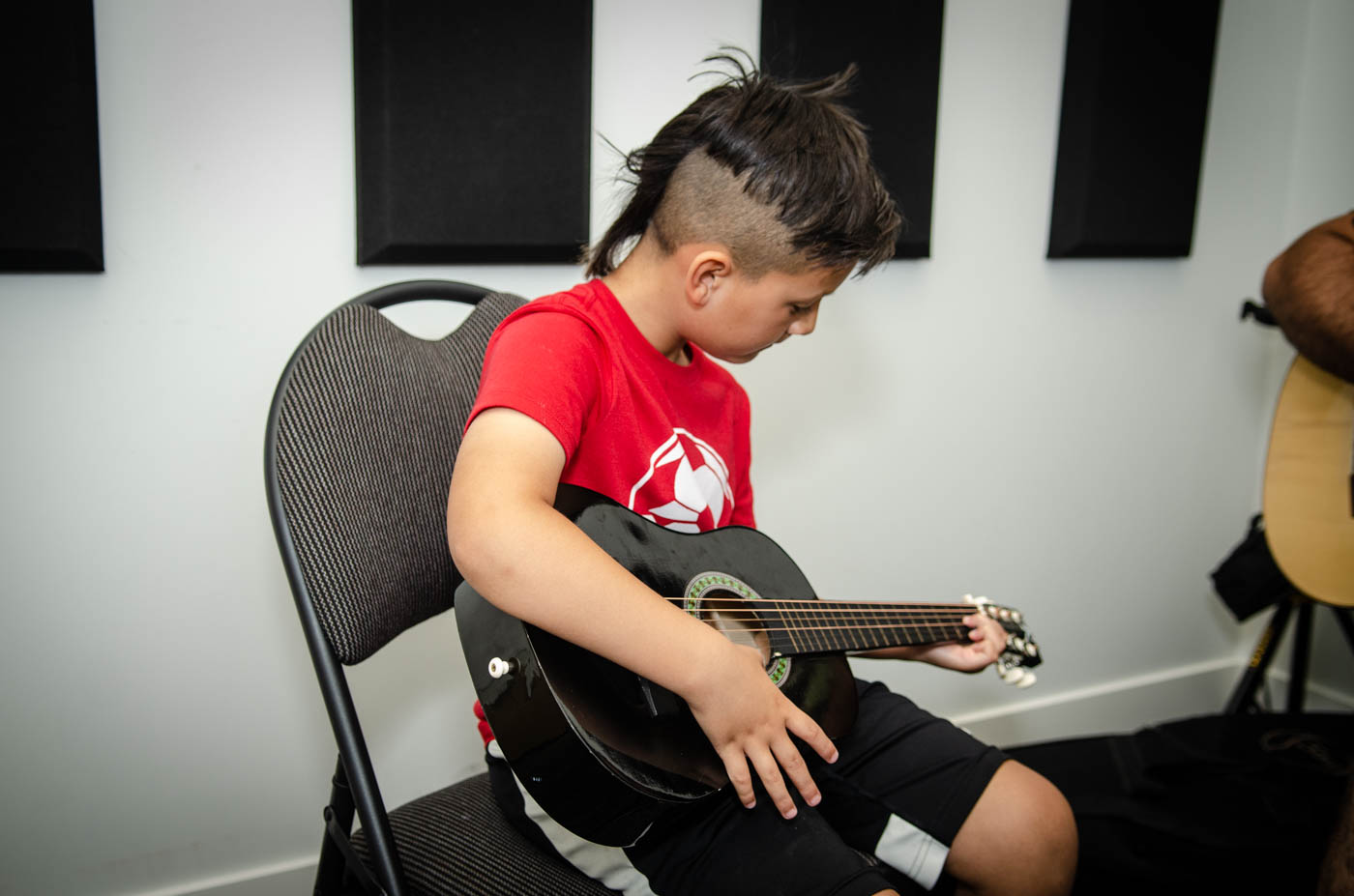 kid in red shirt playing guitar